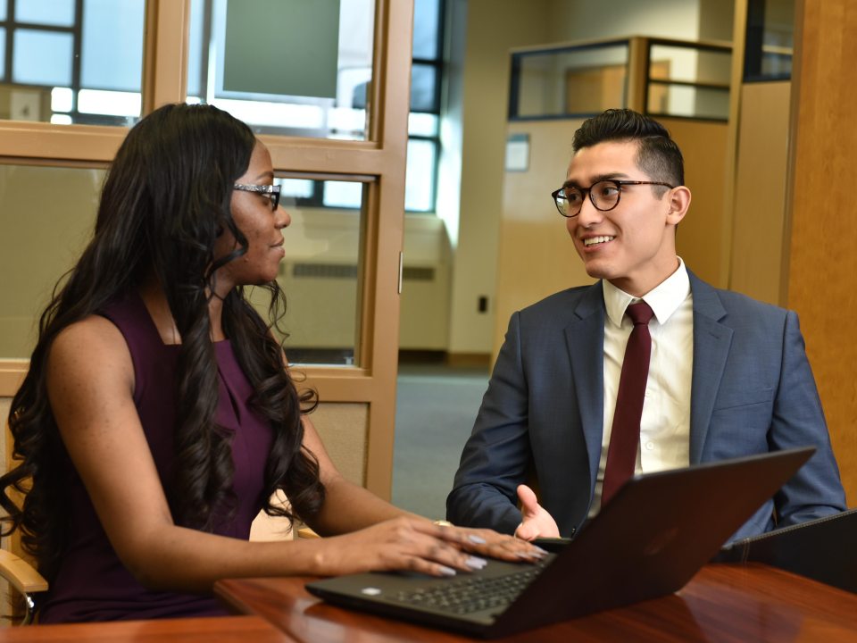 Two business students sitting at a table interacting with each other
