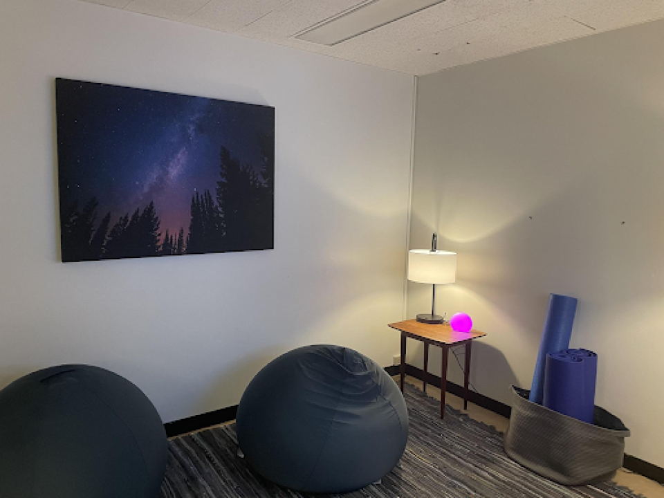 grey room with lit lamp, two blue bean bags, and a picture on the wall