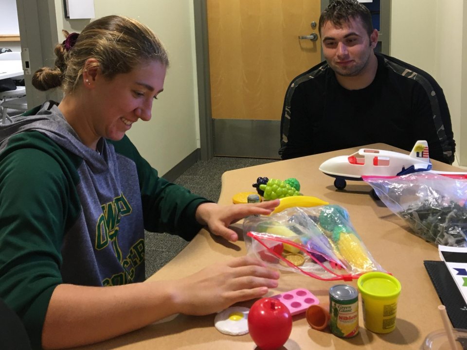 Two students sitting at a table with children's toys on it