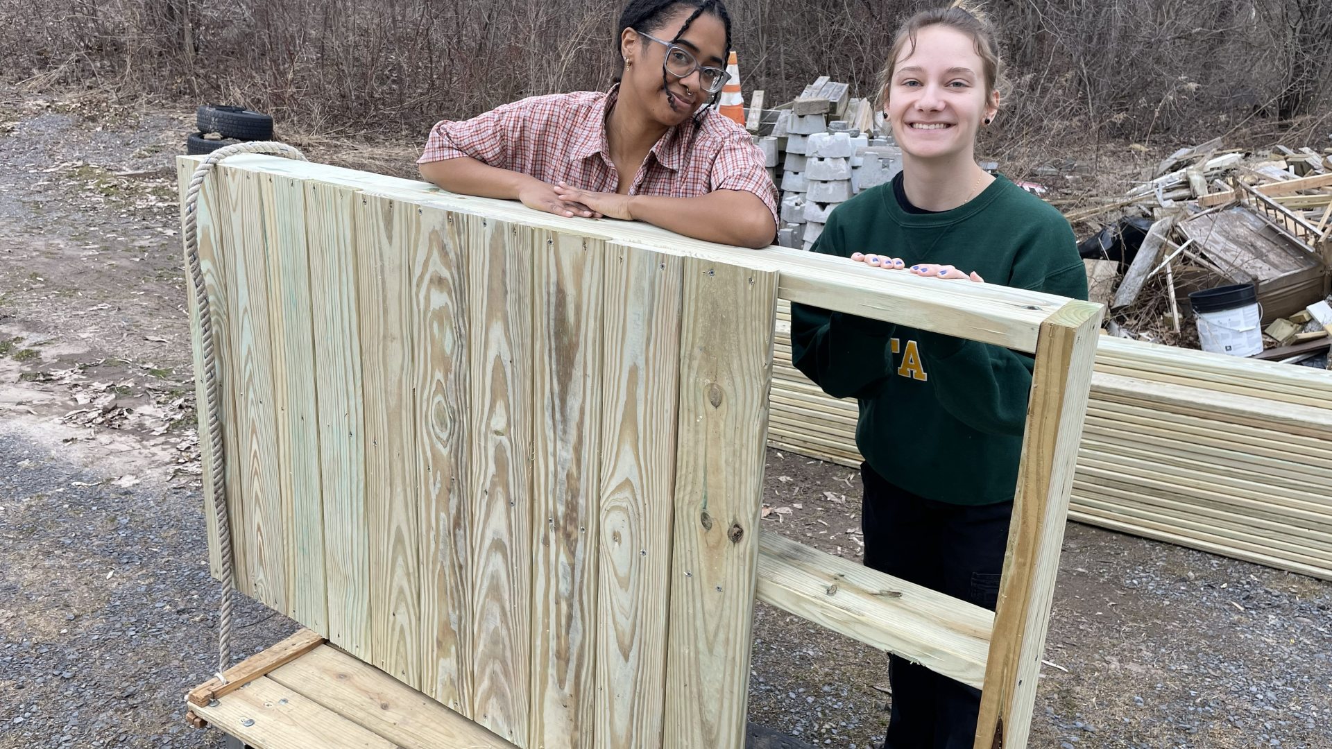 Two female student standing behind a piece of a ramp built with Arise during Day of Service 2024