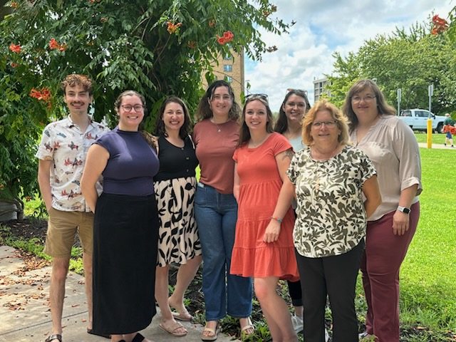 EXCEL team standing in front of vines with orange flowers