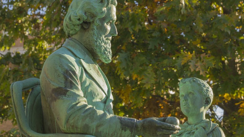 statue of man sitting in chair looking down at boy