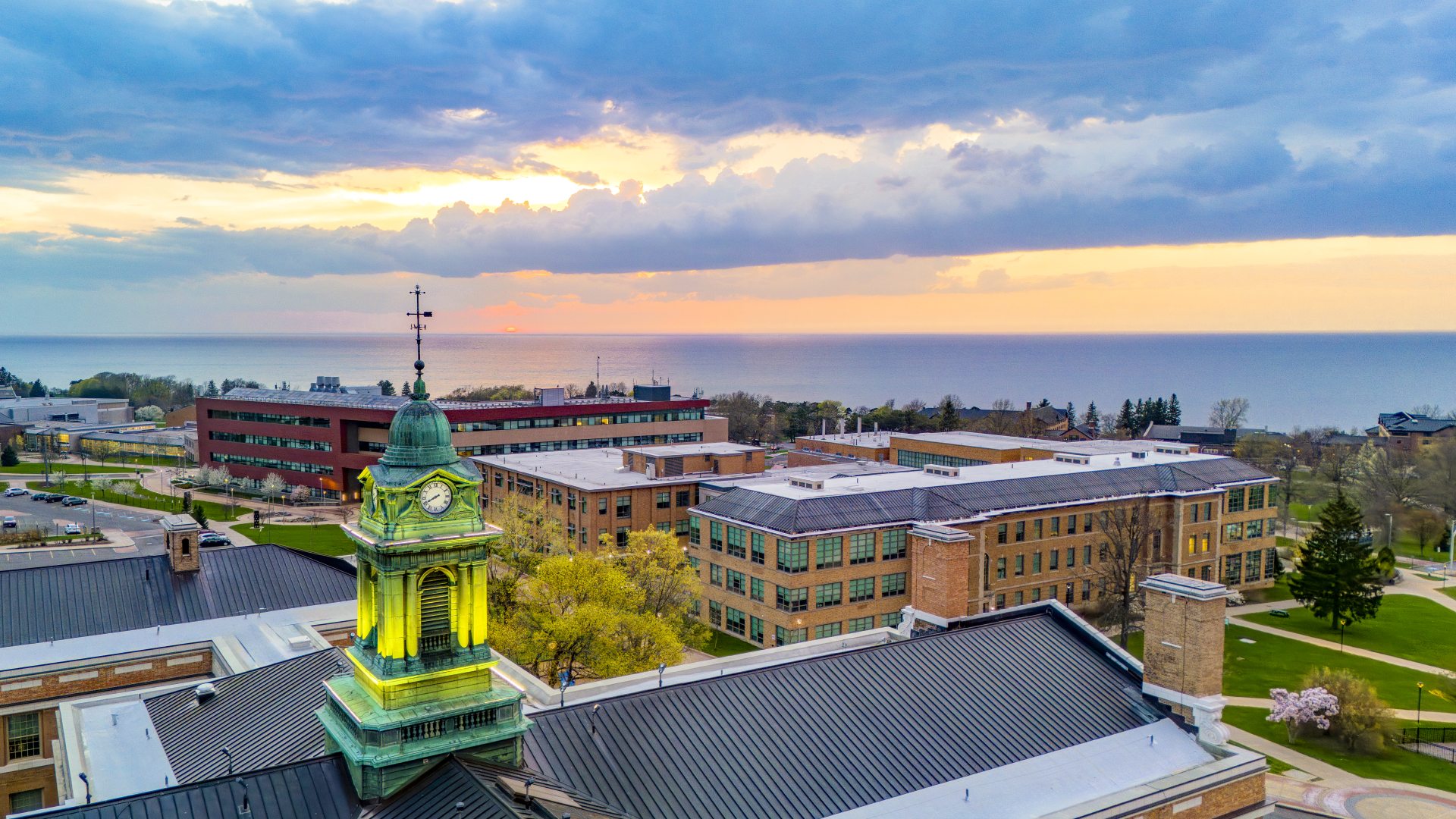 aerial view of SUNY Oswego campus with Sheldon Hall cupola in foreground and lake in background