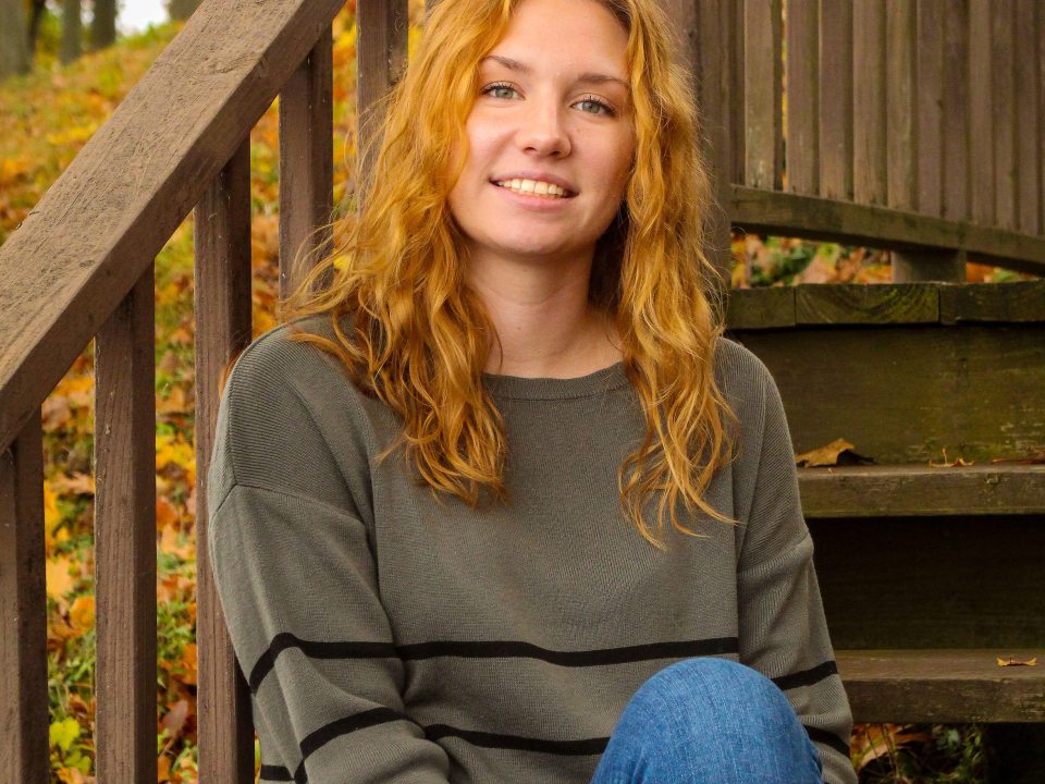 Woman with long blond hair sitting on stairs in the fall