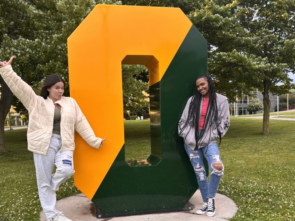 Two students pose by the big O on campus