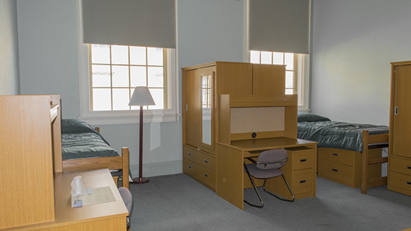a dorm room with desks and beds