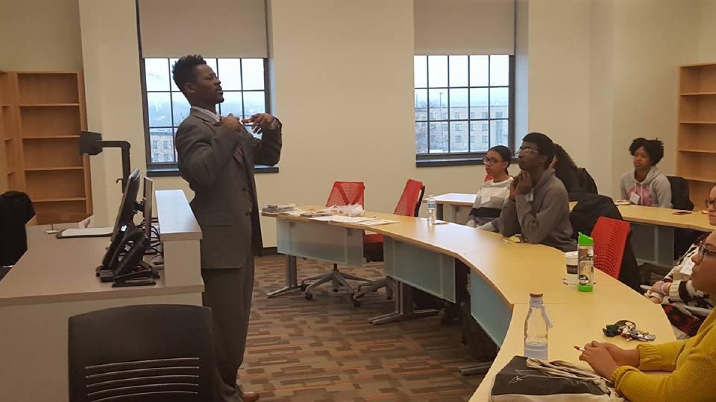 a man speaking at the front of a classroom