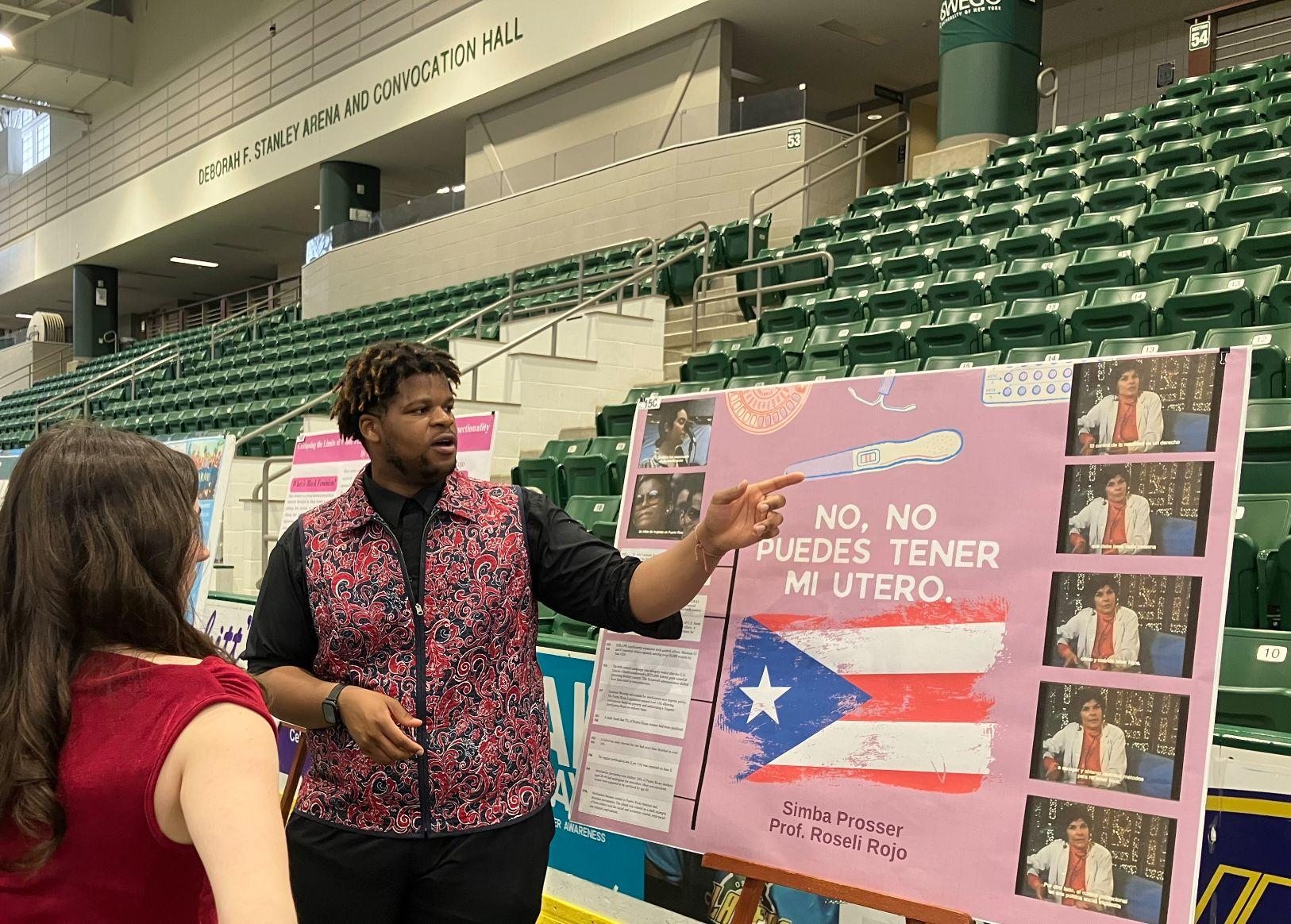 Student presenting at Quest in front of their poster titled No, No Puedes Tener Mi Utero