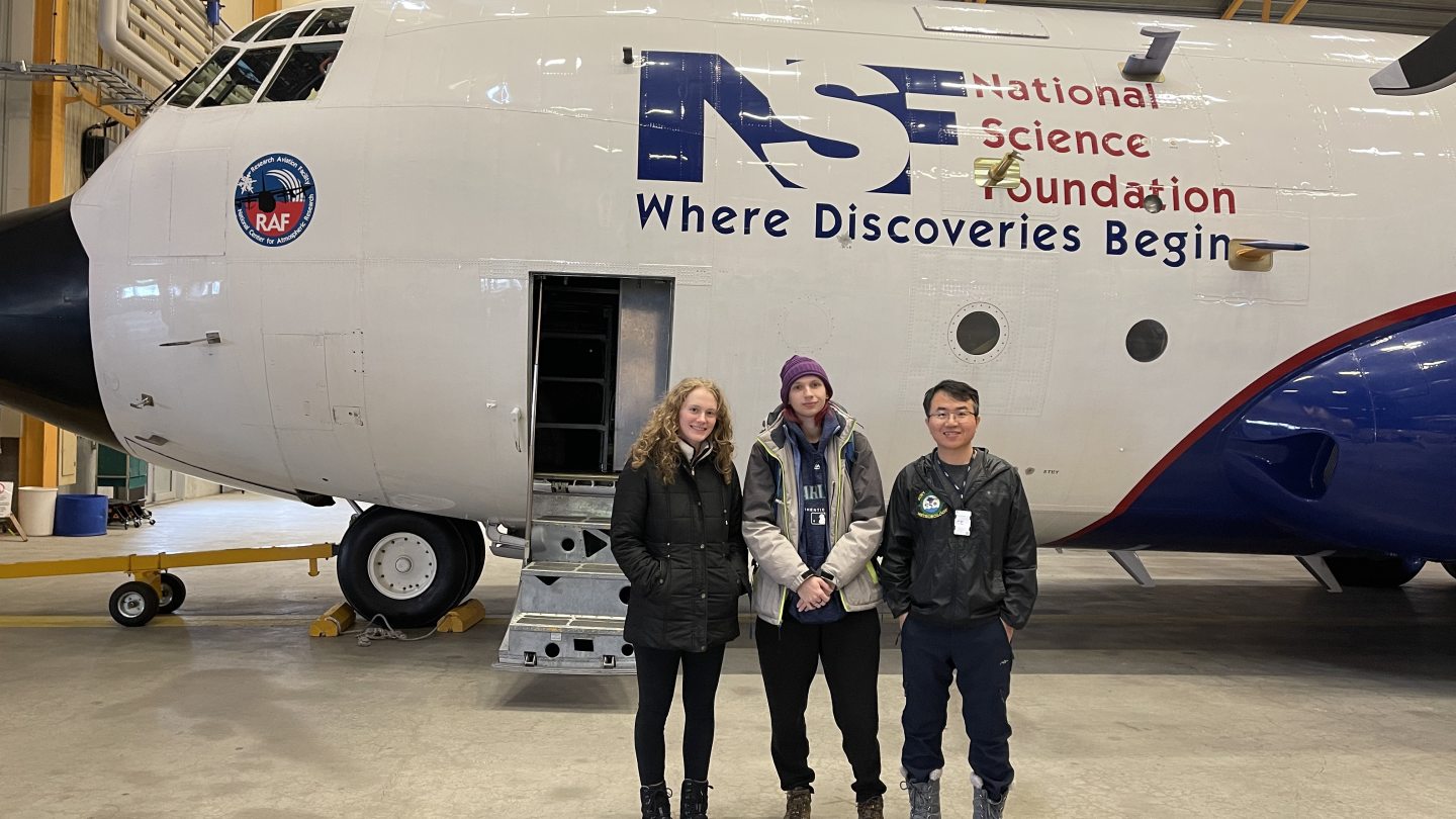 People in front of an airplane inside a hangar