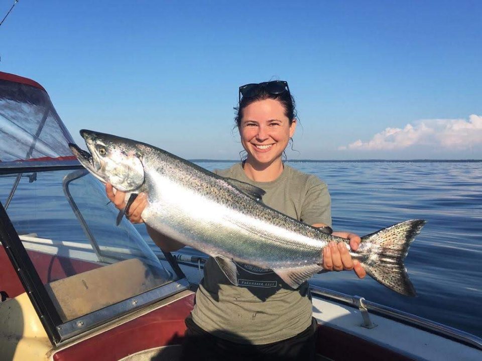 SUNY Oswego biological sciences faculty member Ellen Karboski holds an adult chinook caught on Lake Ontario. Karboski, fellow Oswego faculty member Nicholas Sard and a New York Sea Grant-funded research team are working to assess the competition between stocked and wild salmon in Lake Ontario. (Photo courtesy of Ellen Karboski)