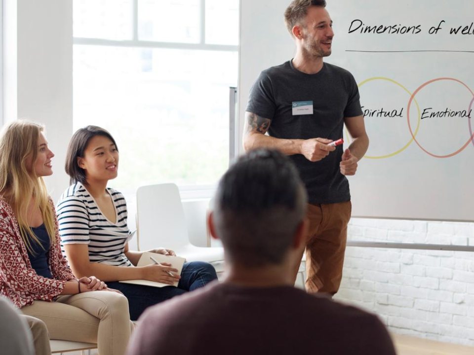 A man standing at a white board in front of a class of students