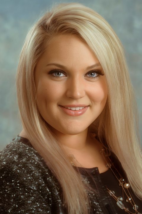 Smiling woman with long blonde hair and blue eyes in a professional headshot.