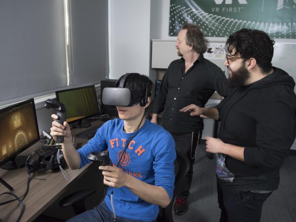 A person using a virtual reality headset with two others observing.
