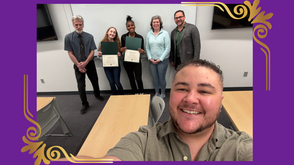 Group photo at the Human Development Honors Reception with faculty and students smiling; two students hold certificates while others stand beside them, celebrating achievements in a classroom setting.