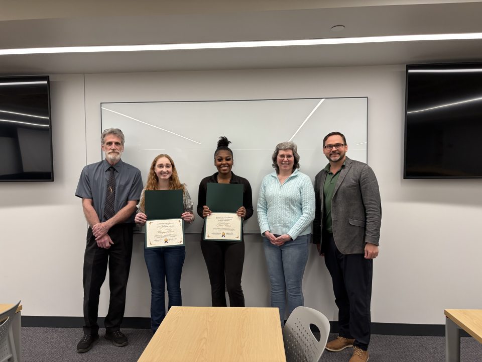 Dr. David Sargent, Morgan Hanna, Tomai Nelson, and Dr. Laura Brown standing together at the Human Development Honors Reception, smiling in a classroom setting as two students hold certificates.