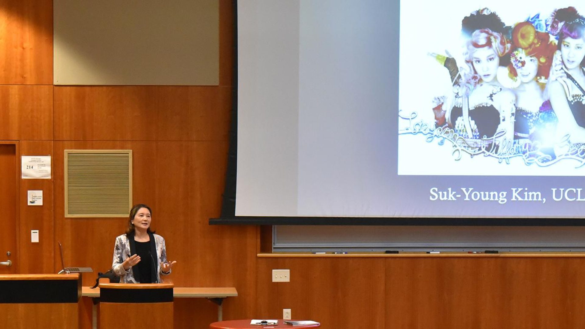 woman standing at a lecture podium infront of an audience