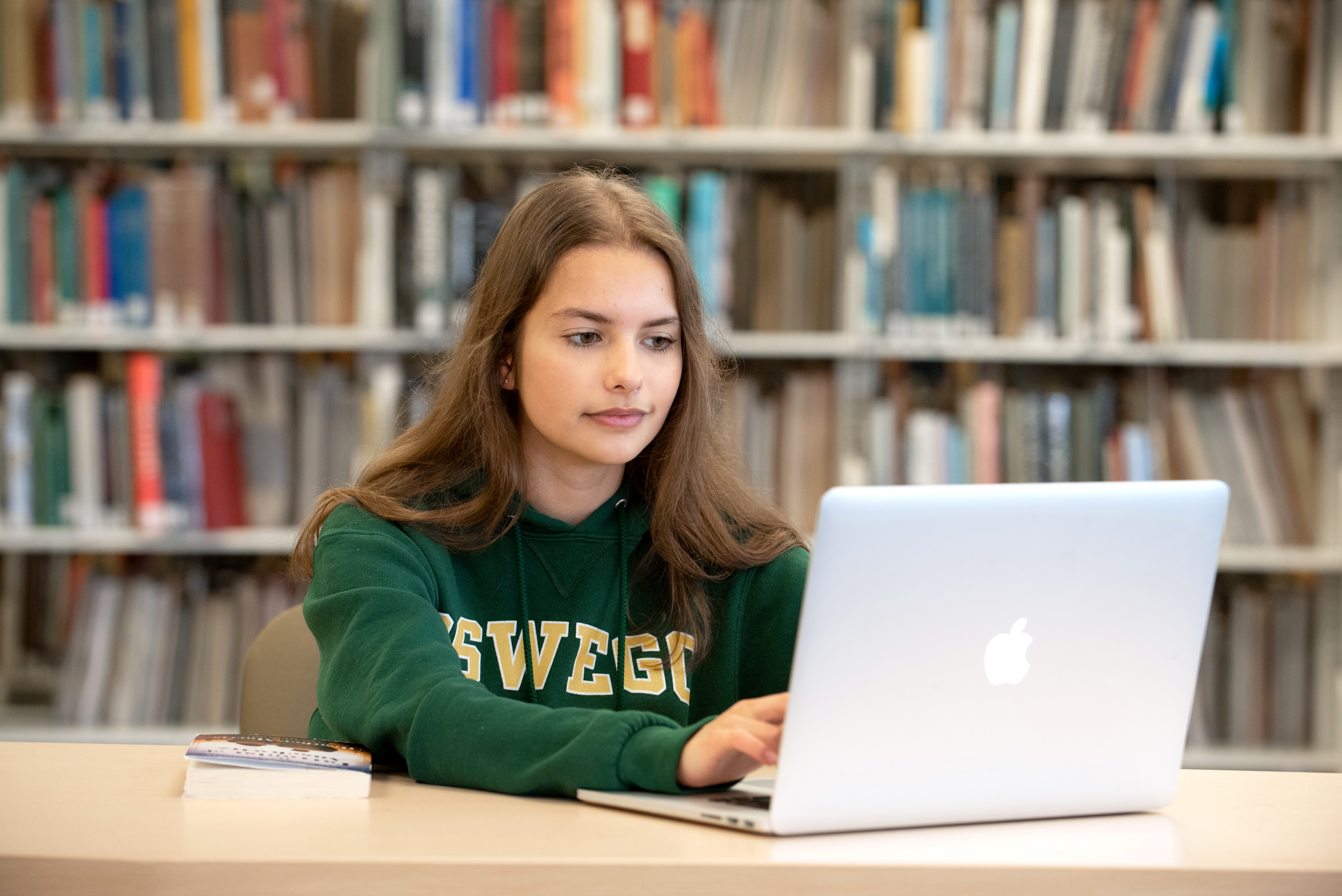 Student in Oswego Sweatshirt Typing on Computer