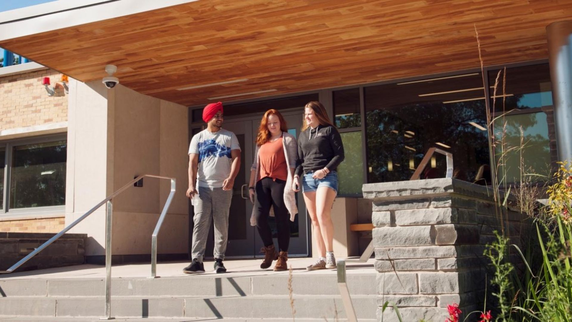 Three students standing out front of a residence building