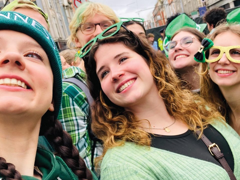 A group of students wearing green glasses and clothing taking a selfie