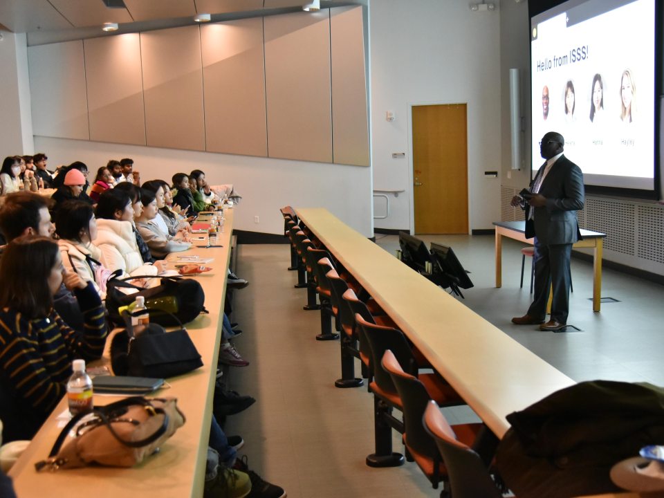 A group of students in a lecture hall, watching a presentation