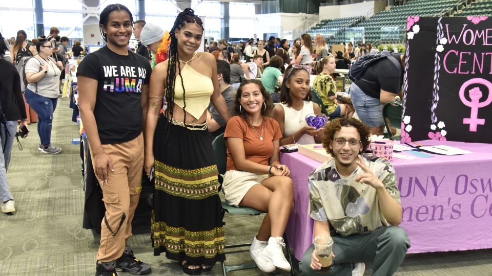 A group of students at a student fair table, promoting the SUNY Oswego Women&#039;s Center