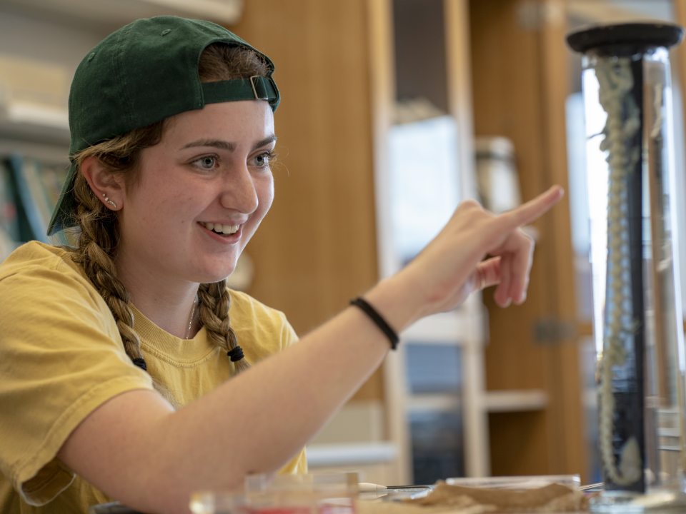 Student examining a preserved vertebral specimen in a clear display cylinder during a laboratory activity.