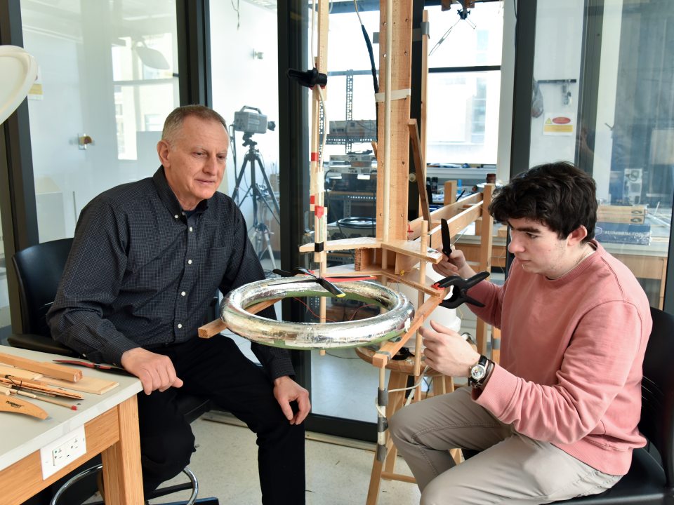 A faculty member works with a student on an engineering experiment in a laboratory workspace.