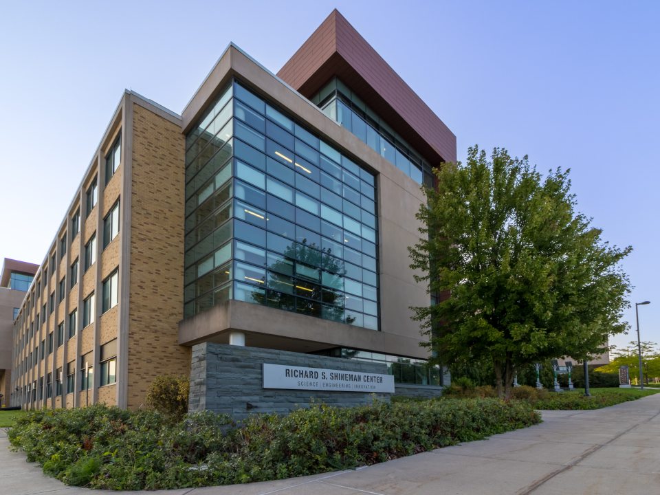 Exterior view of the Richard S. Shineman Center for Science, Engineering and Innovation at SUNY Oswego, featuring modern glass architecture and surrounding greenery.