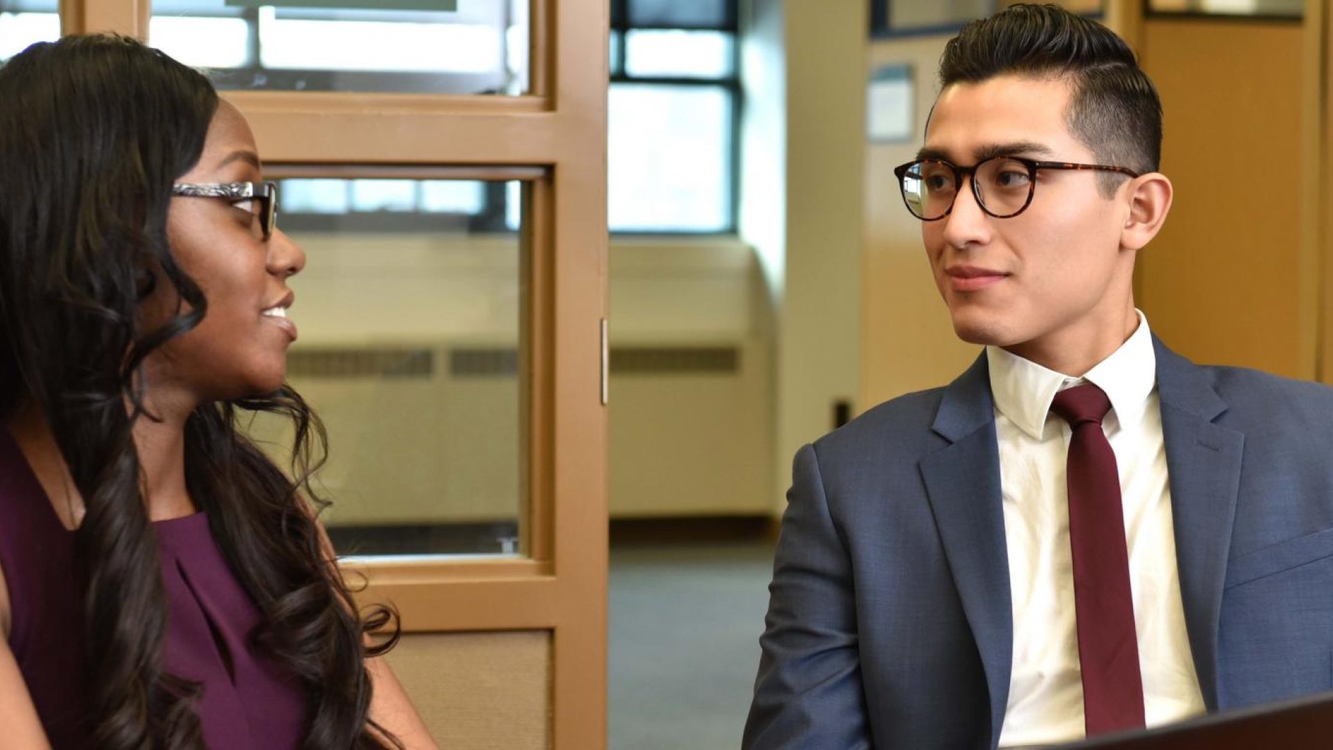 Two students sitting in chairs talking