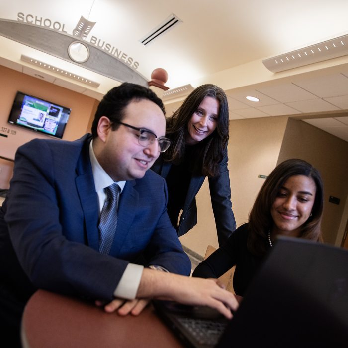 Three people gathered around a laptop
