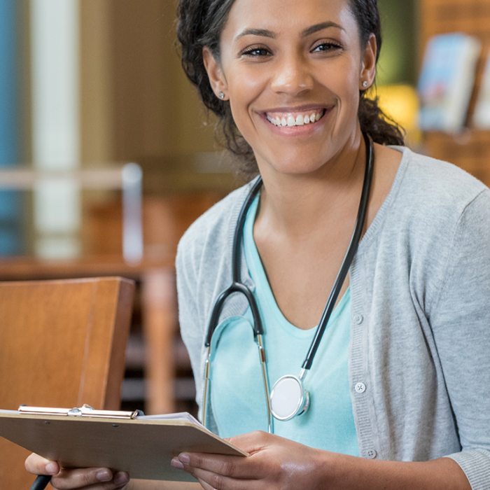 A woman with a stethoscope around her neck, holding a clipboard