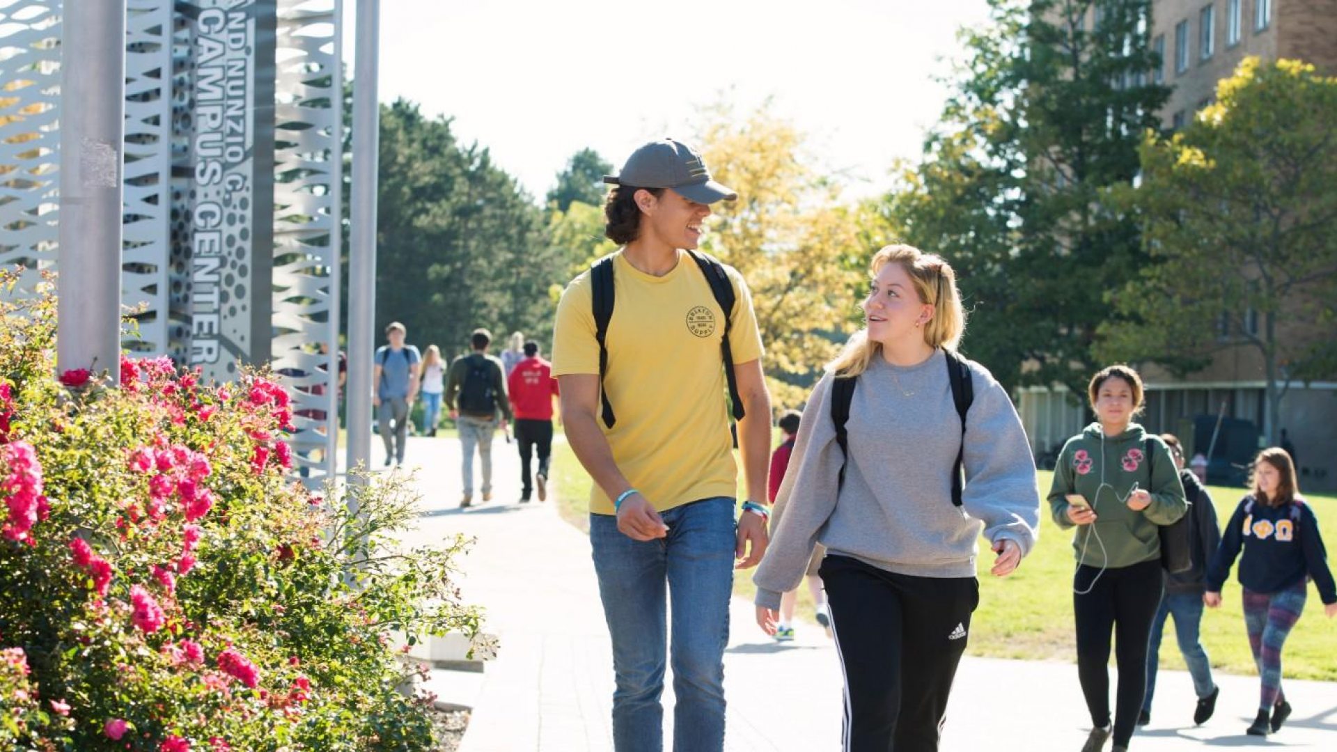 Students seen walking along the sidewalk in front of the Marano Campus Center