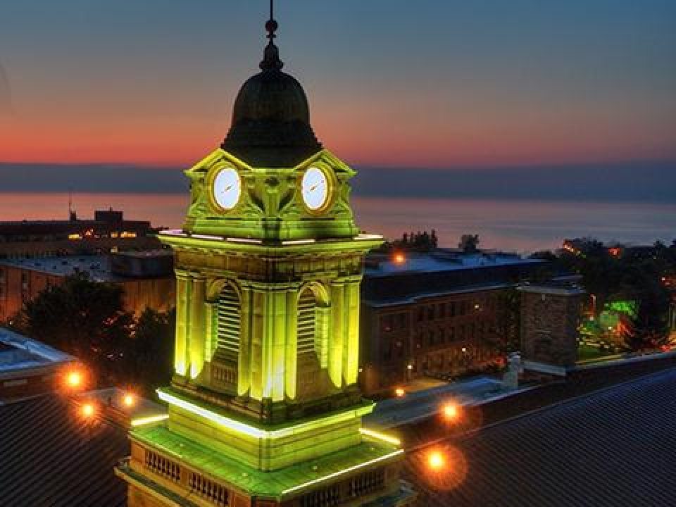 Sheldon Hall cupola, lit up at dusk with a fading sunset seen behind it over the lake