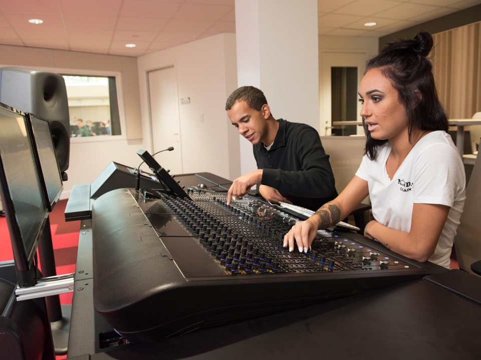 Two students at a soundboard in a recording studio