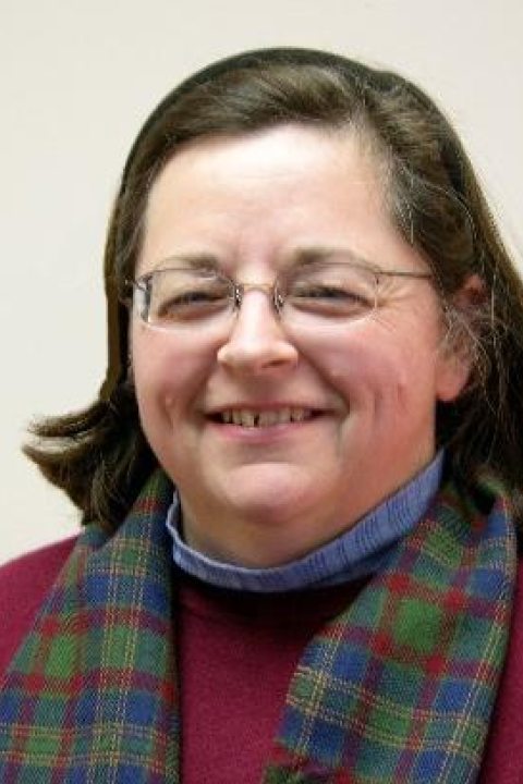 Barbara Bridgers smiling with a red sweater on and a tartan scarf