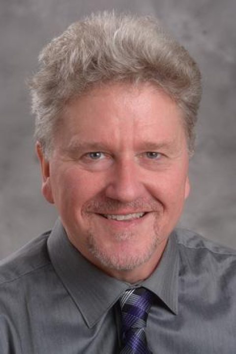 Thomas McGrath in a grey buttonup and a purple and black tie