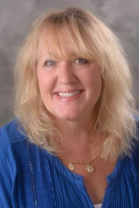 Sally Vanburen is smiling and is wearing a blue top.