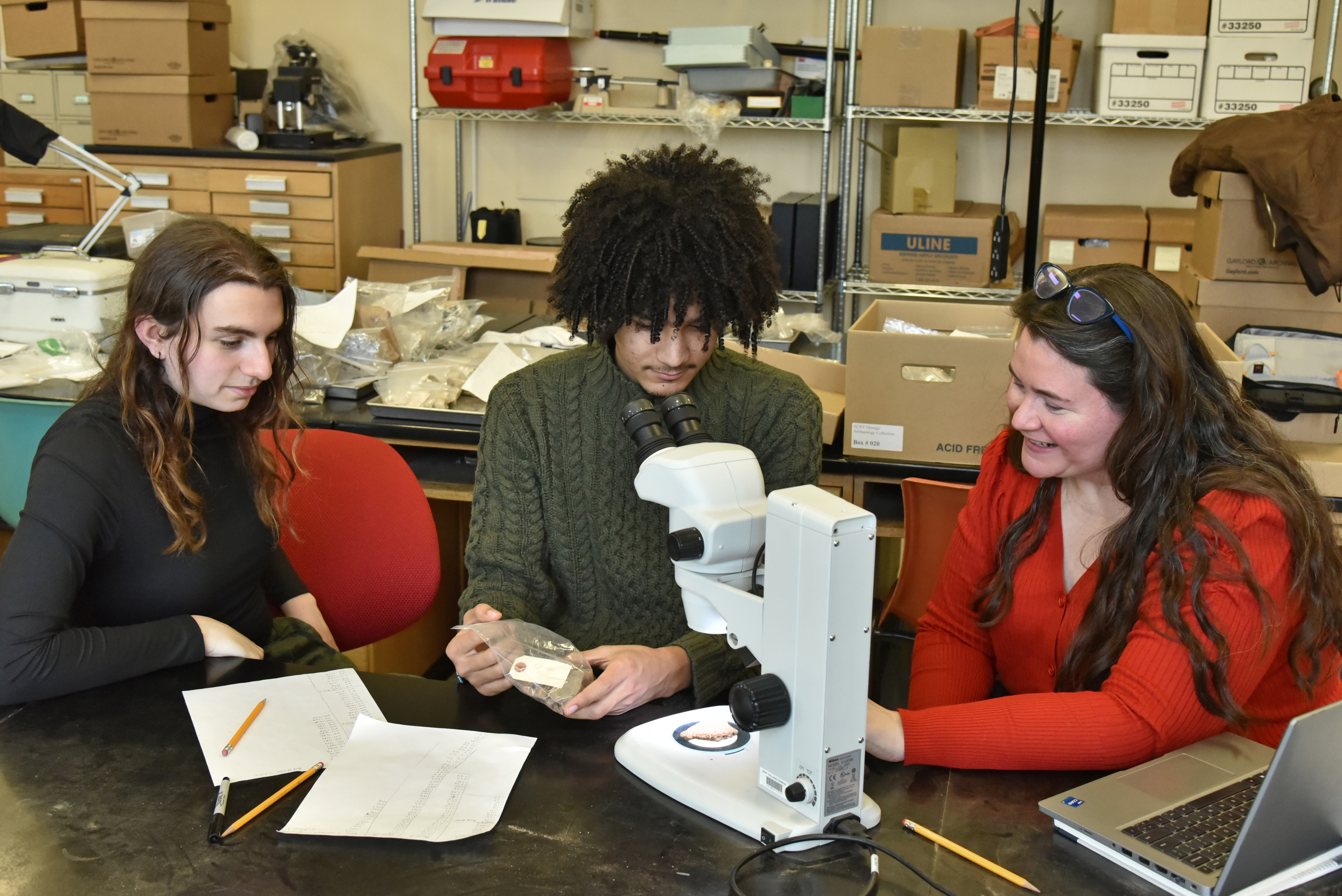 Anthropology faculty member Alanna Ossa (right) prepares for a large research project exploring the history of open market exchange and economic development in the Gulf Coast area of Veracruz, Mexico, that also connects to modern community-building and student research. Here Ossa works with, from left, Mackenzie Schmitt, a junior majoring in anthropology and in global and international studies, and Rudy Arietta, a senior anthropology major, in a Mahar Hall anthropology lab.