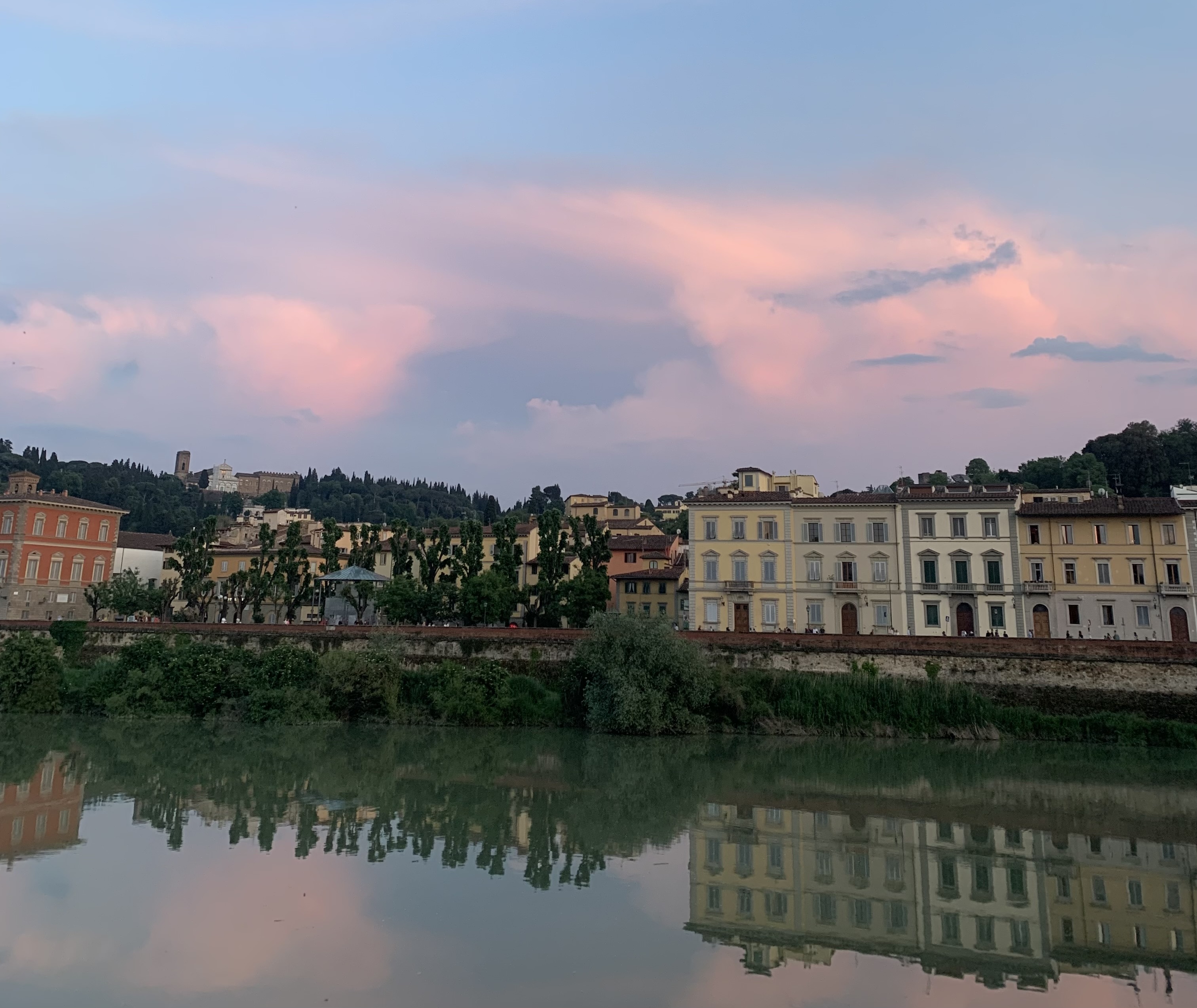 A scenic sunset view in Florence, Italy. A beautiful pink, purple and blue sunset in Florence, Italy. The buildings reflect off of the clear blue water.