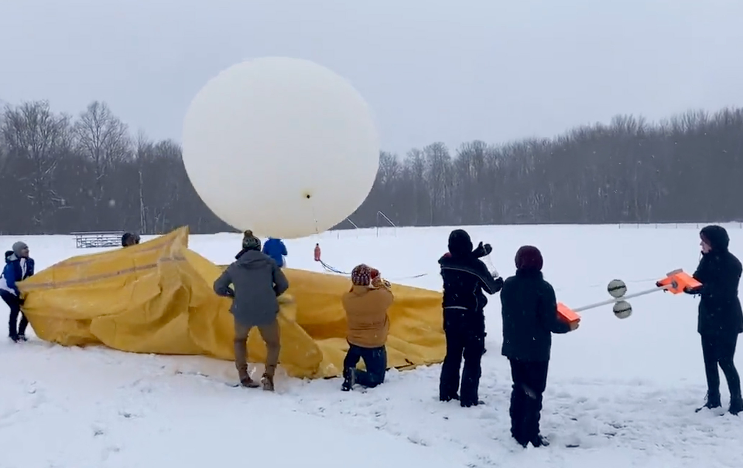 Students taking part in the Lake-Effect Electrification study launch a huge weather balloon with attached instrumentation to measure conditions inside a winter storm cloud.