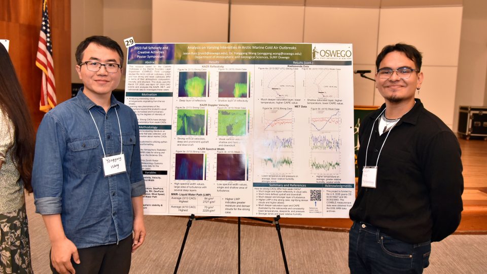 SUNY Oswego meteorology professor Yonggang Wang and his student Jason Ruiz stand in front of their poster presentation on arctic cold air outbreaks.