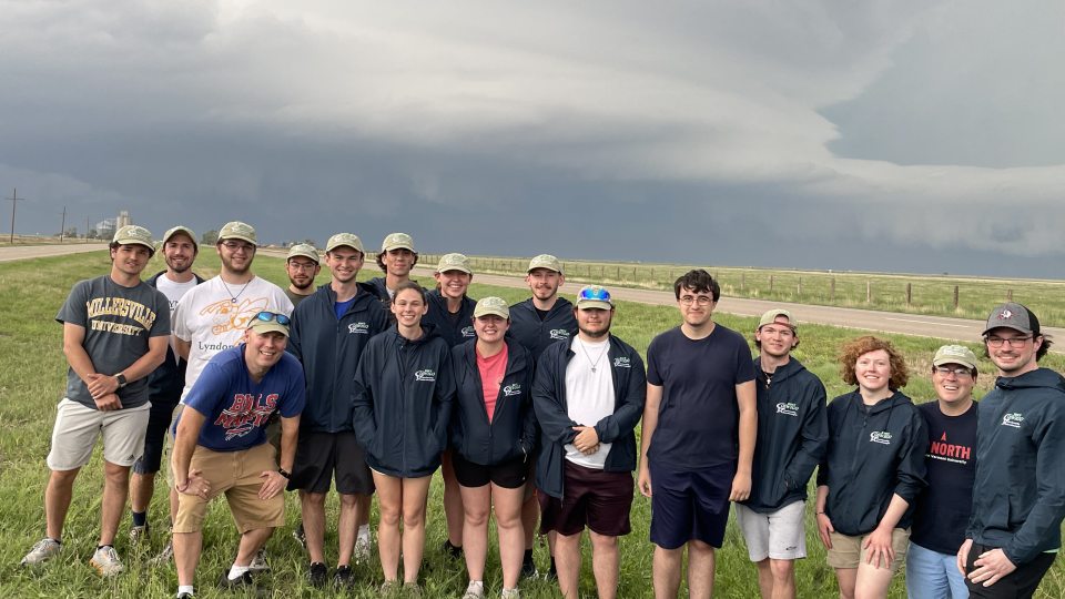 Professor Scott Steiger and his class stand in front of a stormy sky on their storm-chasing trip.