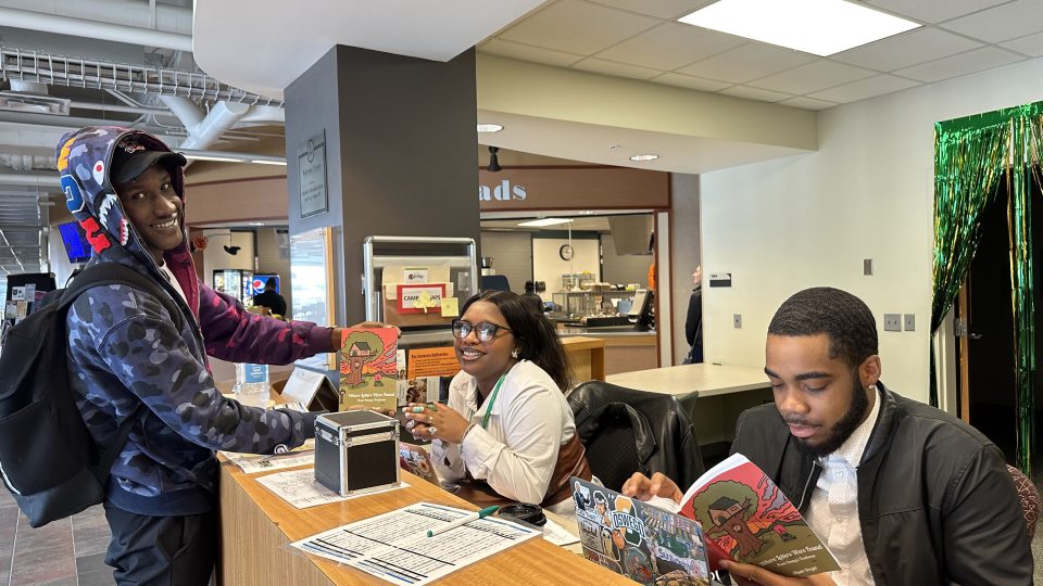 Aliyah Wright and two co-workers look over her book of poetry