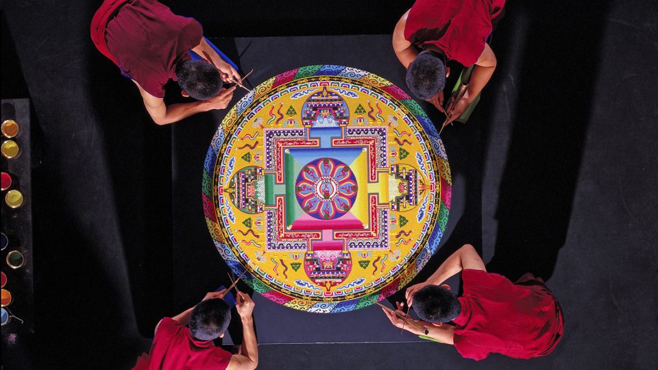 Tibetan monks of the Drepung Loseling Monastery work on sand art painting