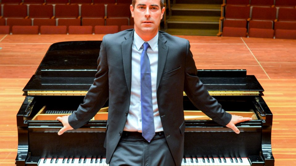 Robert Auler stands at a piano