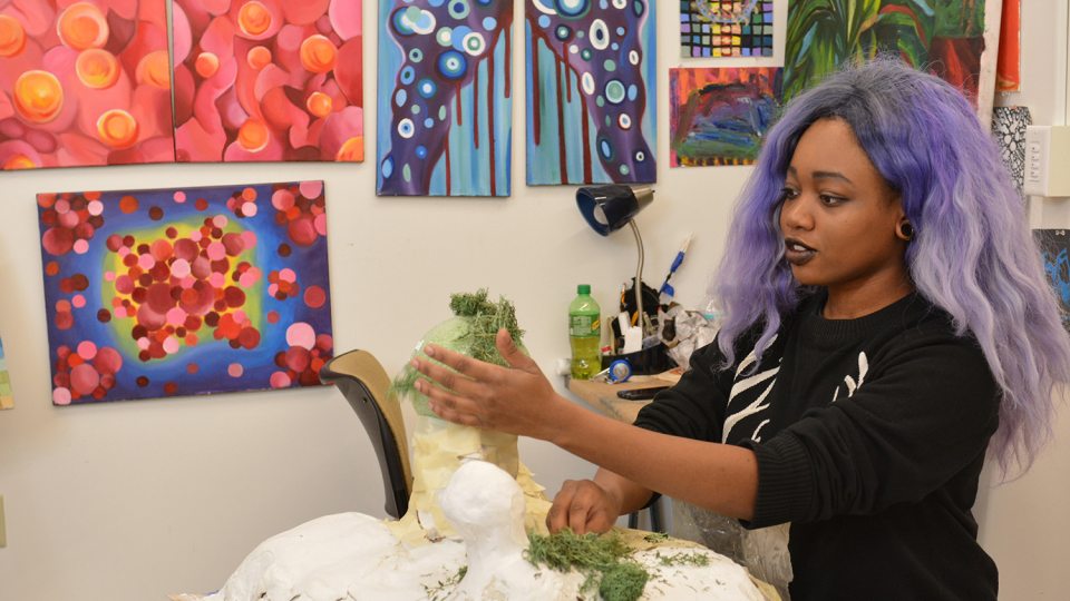 Star Daniels applies moss to a sculpture