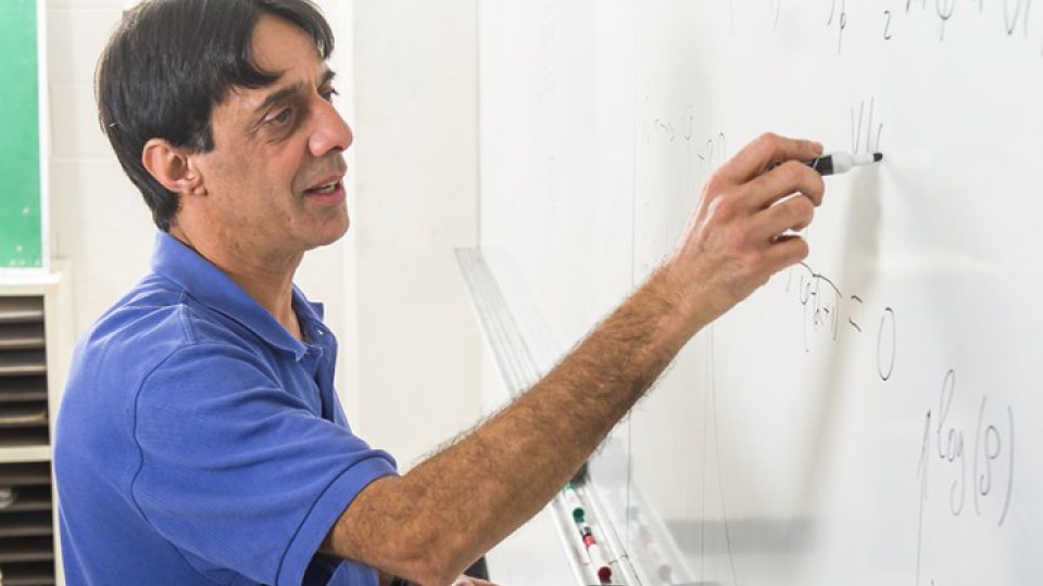 Bharat Ratra writes on a whiteboard