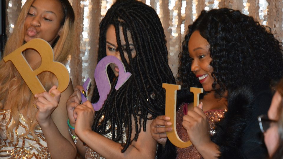Students hold up letters B S U