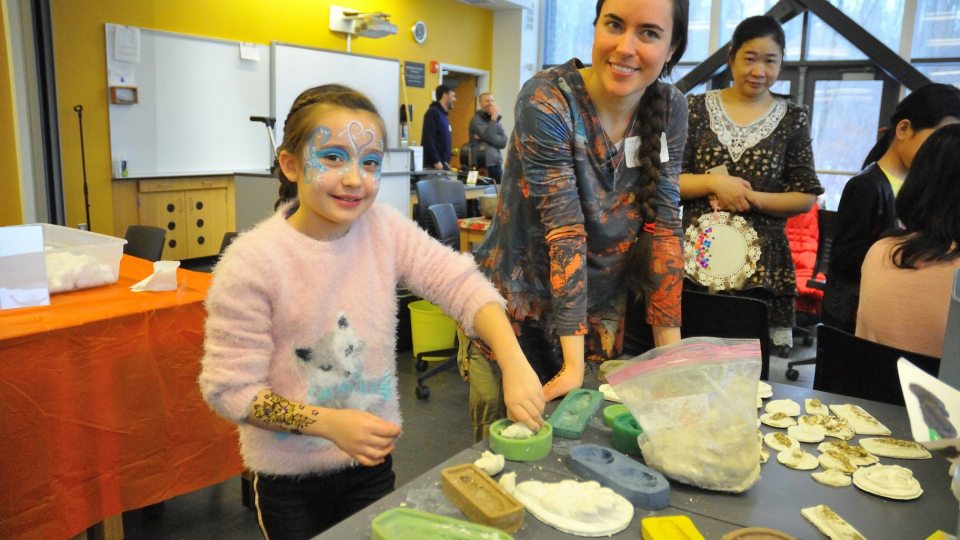 Rice Creek visitor Lexie Prosser works with the field station's Kristen Hansen to make clay animal tracks at a preview Celebrate Snow