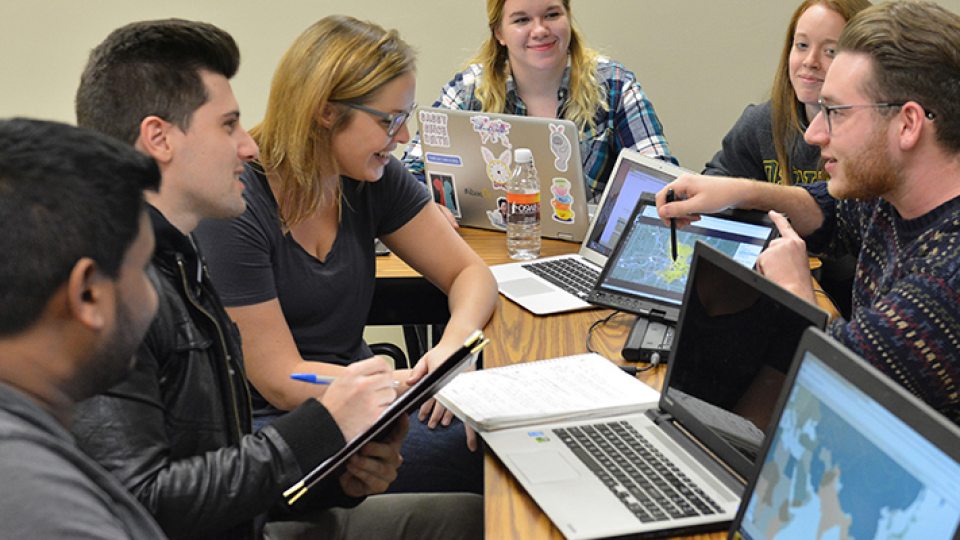 Students in front of computers discussing mapping project